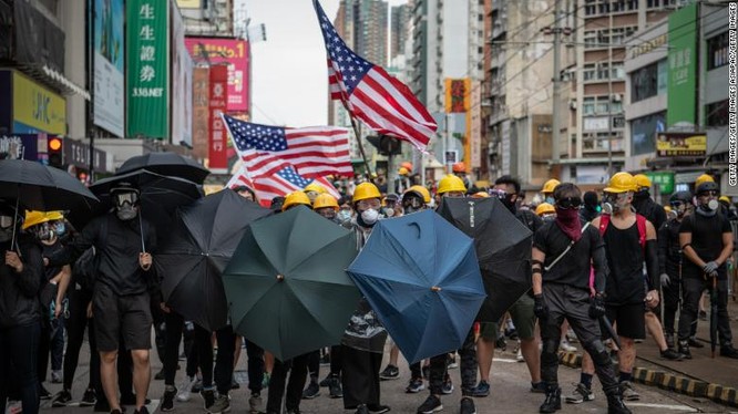 Người biểu tình mang theo cờ Mỹ khi tuần hành ở quận Yuen Long hôm 27/7 (Ảnh: CNN)