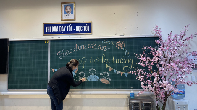 Cô giáo viết bảng chào đón học sinh quay trở lại trường (Ảnh - Phòng GD&ĐT quận Ba Đình) 