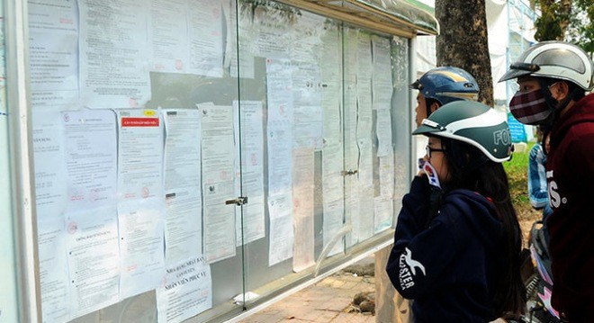 Người tìm việc, công nhân đang xem thông báo tuyển dụng đặt trong khuôn viên Khu công nghiệp Amata (P.Long Bình, TP Biên Hòa, Đồng Nai) ngày 9-3