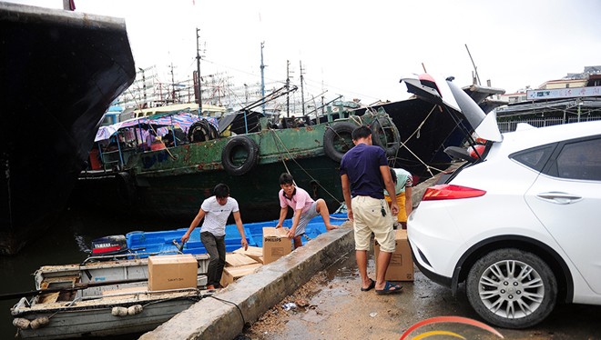 Ngư dân cảng Tam Á, Hải Nam, chất lương thực lên thuyền con, chở ra ngoài tàu lớn. Ảnh: HiNews