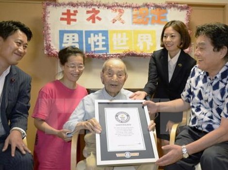 Cụ Yasutaro Koide (giữa) nhận giấy chứng nhận Kỷ lục Thế giới Guinness cụ ông cao tuổi nhất thế giới tại Nagoya ngày 21/8 vừa qua. (Ảnh: Kyodo/TTXVN)