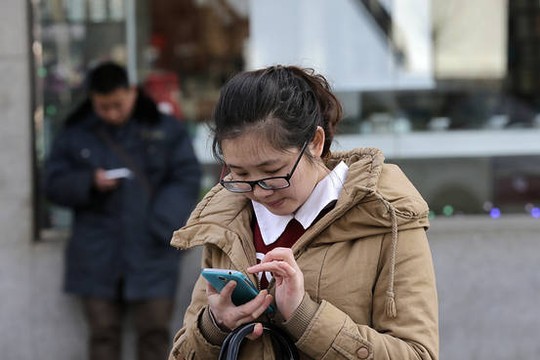 Một cô gái sử dụng điện thoại trên đường phố Bắc Kinh. Ảnh: AP