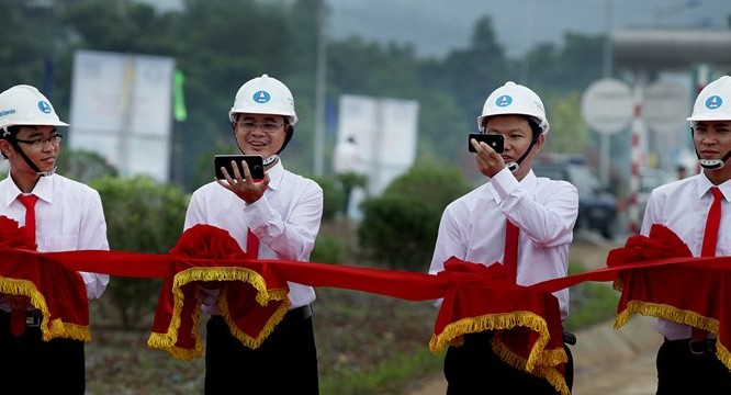 Những cán bộ ngành Giao thông tranh thủ chụp ảnh selfie bằng điện thoại thông minh trong khi đang nâng dải băng đỏ chờ cắt băng khánh thành cao tốc Nội Bài - Lào Cai vào tháng 9/2014.