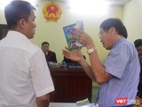 Họa sĩ Lê Linh (áo trắng) và ông Nguyễn Vân Nam (người đang cầm cuốn sách) - đại diện cho công ty Phan Thị với những trao đổi gay gắt tại tòa