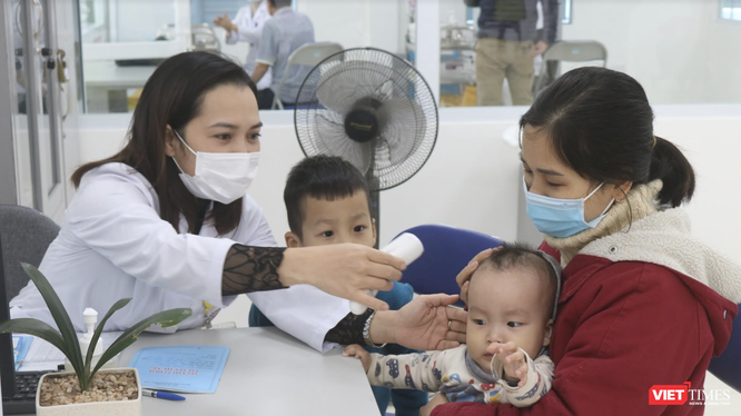 Nhân viên y tế kiểm tra nhiệt độ cho trẻ (Ảnh - Minh Thuý) 