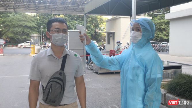 Nhân viên y tế kiểm tra nhiệt độ của người dân trước khi vào bệnh viện (Ảnh - Minh Thuý) 