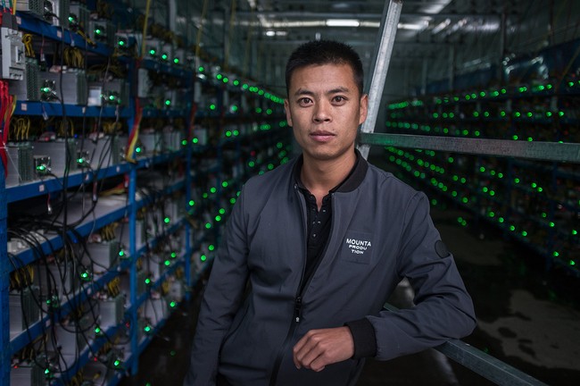 Hình 3: Kun - chàng trai người Tây Tạng – là chủ nhân của khu mỏ này đang chụp ảnh giữa hai hàng “trâu cày” Bitcoin. Anh cho biết anh được biết về Bitcoin thông qua một người bạn và đã bắt đầu đầu tư vào lĩnh vực này kể từ năm 2015