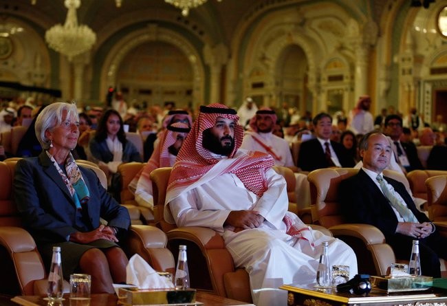 Người đàn ông ngồi ở giữa chính là hoàng tử Ả Rập Mohammed bin Salman. Bên phải hoàng tử là ông Masayoshi Son, người đồng sáng lập và điều hành ngân hàng Soft Bank. Bên trái chính là bà Christine Lagarde, giám đốc điều hành Quỹ tiền tệ quốc tế (IMF)