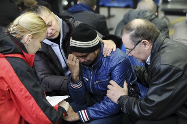 Các bác sĩ tâm lý an ủi người nhà nạn nhân tại sân bay. Ảnh: Reuters