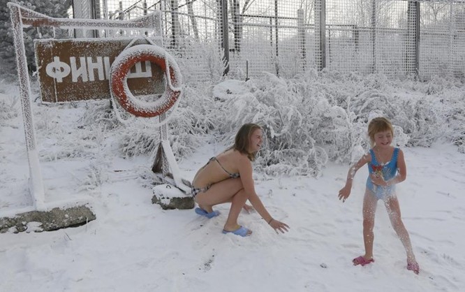 Hai chị em Yulia Klimenkova (16 tuổi) và Liza Broverman (6 tuổi) đều là thành viên của câu lạc bộ bơi mùa đông Cryphile đang chơi đùa với tuyết trước khi tắm sông Yenisei ngày 15/11/2015.