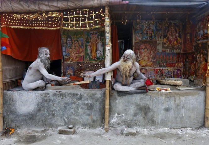 Naga Sadhus, người thánh Hindu chia nhau điếu thuốc trong trại tạm gần nơi hợp lưu của sông Hằng và vịnh Bengal, trước lễ hội 