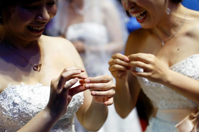 Cặp đôi trao nhẫn cưới cho nhau trong buổi tiệc cưới đồng tính tập thể ở Đài Bắc hôm 25/5 (Ảnh: Reuters)