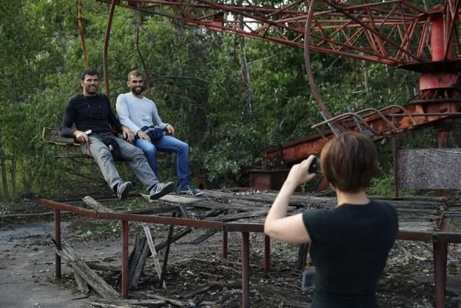 Du khách chụp ảnh lưu niệm tại nơi từng là khu vui chơi ở thị trấn Pripyat năm 2017 (Ảnh: Newsweek)