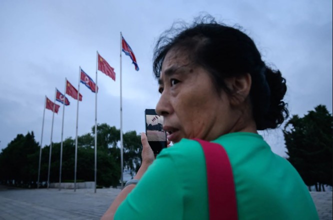 Một người phụ nữ sử dụng smartphone chụp ảnh quảng trường Kim Il Sung ở thủ đô Bình Nhưỡng (Ảnh: AFP)