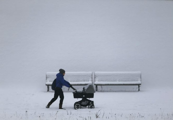 Người phụ nữ đẩy xe đẩy dọc theo bờ sông Spree phủ đầy tuyết trắng sau đợt tuyết rơi dày ở Berlin, Đức, ngày 6/1.