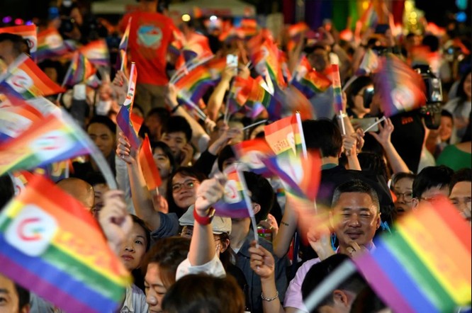 Nhiều người giơ cao lá cờ cầu vầu trong một sự kiện kết hôn tập thể tổ chức ngay trước Phủ Tổng thống ở Đài Bắc hôm 25/5 (Ảnh: AFP)