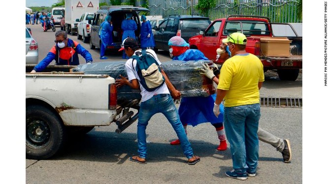 Nhóm người mặc đồ bảo hộ khiêng quan tài lên xe trước cổng một bệnh viện ở Guayaquil (Ảnh: CNN)