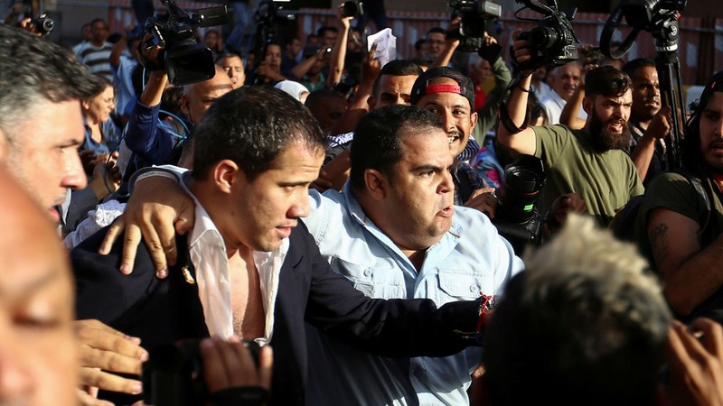 Ông Juan Guaido được hộ tống ra xe để thoát khỏi đám đông người biểu tình ở sân bay (Ảnh: Sputnik)