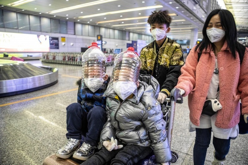 Hành khách ở Quảng Châu tự tạo mặt nạ phòng hộ bằng vỏ thùng đựng dầu ăn (Ảnh: EPA)