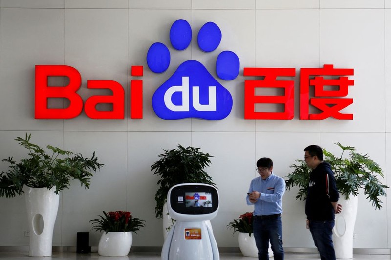 Khách giao dịch tương tác với robot AI của Baidu gần logo công ty tại trụ sở ở Bắc Kinh, Trung Quốc ngày 23/4/2021. Reuters