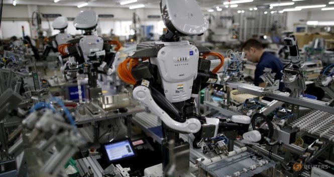 Robot cùng làm việc với nhân viên trong dân chuyền lắp ráp tại một nhà máy của công ty Glory ở phía bắc Tokyo - Ảnh: Reuters