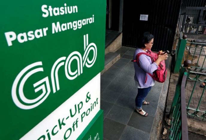 Một phụ nữ dùng ĐTDĐ gọi xe của hãng Grab tại Jakarta