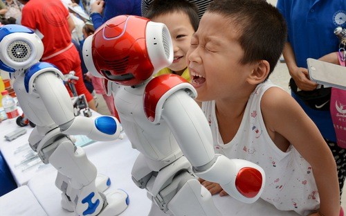 Những em bé đang nô đùa với robot trong một triển lãm ở Trung Quốc - Ảnh: Business Insider.