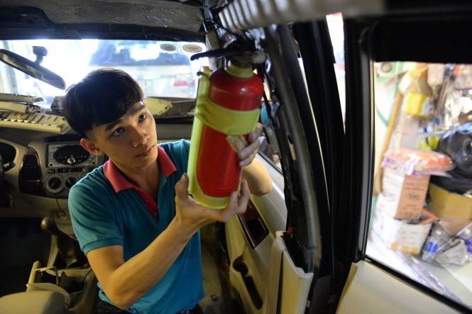 Nhân viên cửa hàng bán bình chữa cháy tại TP.HCM lắp đặt bình chữa cháy trên ôtô của khách hàng - Ảnh: Hữu Khoa