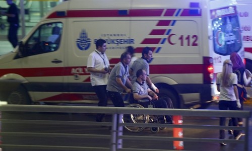 Nhân viên y tế hỗ trợ một người ngồi xe lăn rời khỏi sân bay Ataturk. Ảnh: Reuters.