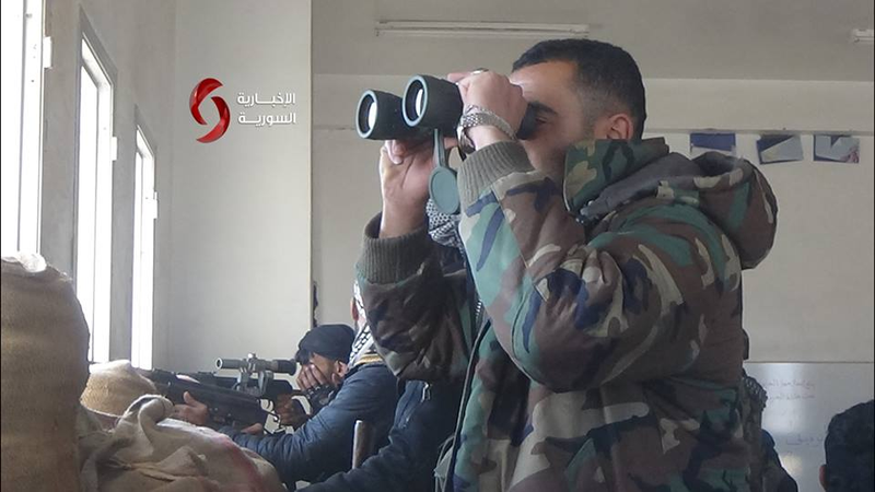 Một sĩ quan Syria đang theo dõi tình hình địch trên chiến trường thành phố Daraa