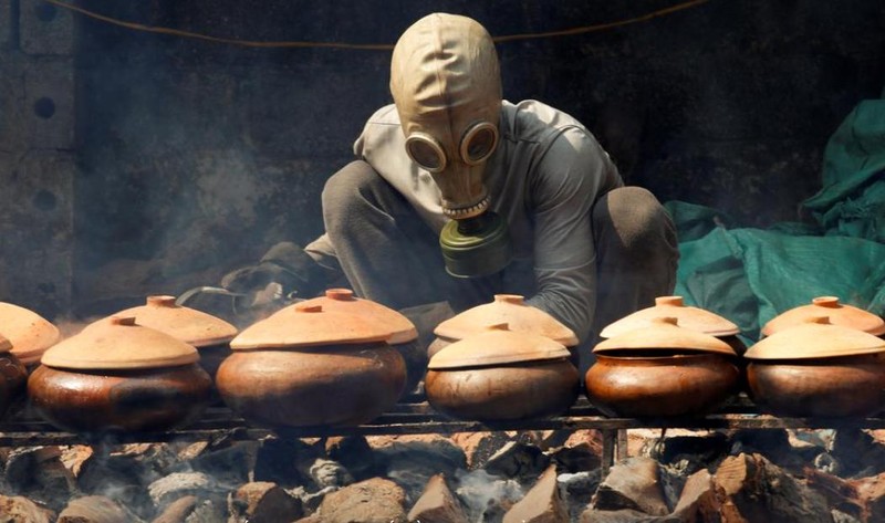 Anh Bùi Văn Cường đeo mặt nạ phòng độc để kho cá trắm (ảnh: Reuters)