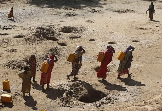 Những người phụ nữ đang mang các can nước được lấy từ giếng đào trên cát dọc theo bờ sông Shabelle, đây là khu vực rất thiếu nước trong mùa hạn tại Somali (Ảnh Reuters)
