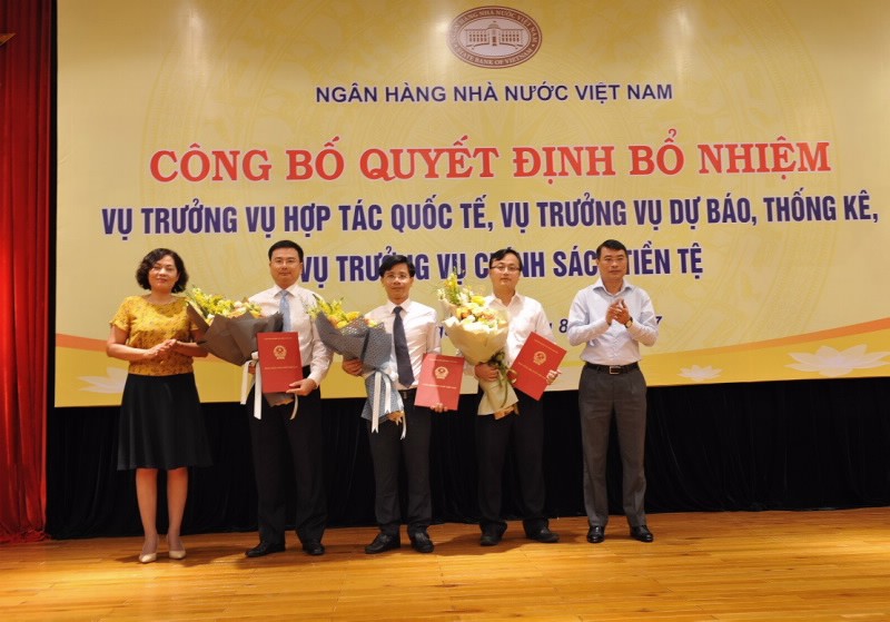 Thống đốc Lê Minh Hưng cùng Phó Thống đốc Nguyễn Thị Hồng trao Quyết định và tặng hoa chúc mừng các tân Vụ trưởng. (Ảnh: SBV)