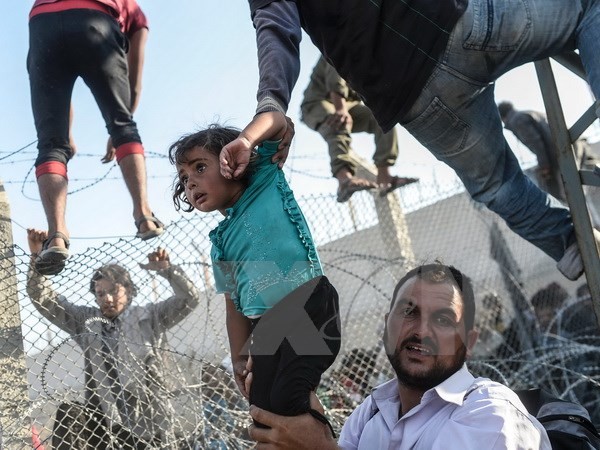 Người tị nạn Syria vượt qua hàng rào dây thép gai tại biên giới Thổ Nhĩ Kỳ. 