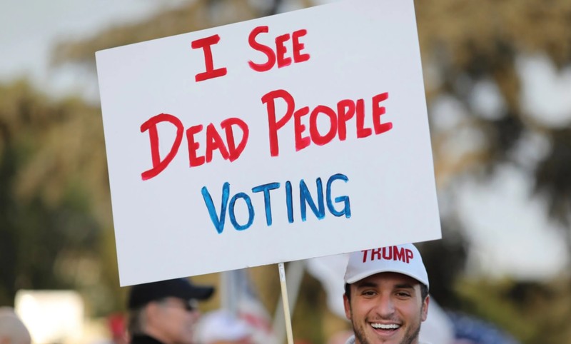 Một người ủng hộ Trump giơ tấm biển với dòng chữ: "Tôi thấy người chết đi bỏ phiếu" (Ảnh: Telegraph)