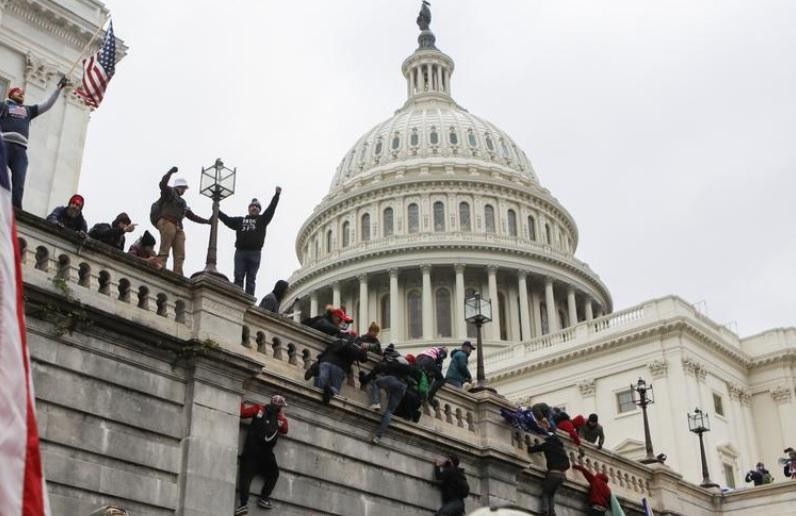 Người biểu tình trèo lên tường tòa nhà Quốc hội Mỹ hòng thâm nhập vào bên trong (Ảnh: Reuters)