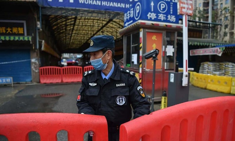 Một nhân viên bảo an đứng giám sát bên ngoài chợ hải sản Hoa Nam (Ảnh: AFP)
