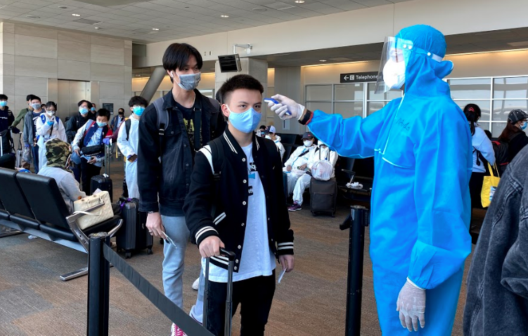Nhân viên y tế kiểm tra nhiệt độ của hành khách ở sân bay (Ảnh - BYT) 