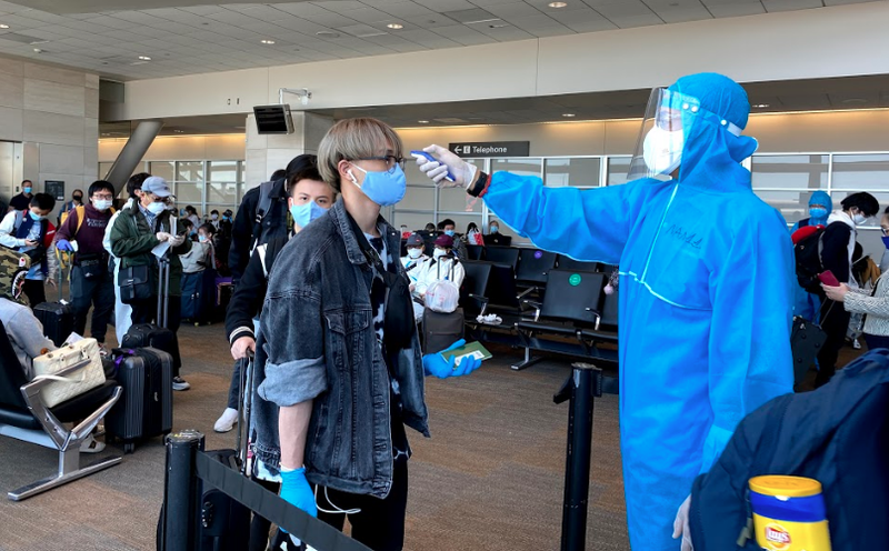 Nhân viên y tế đo thân nhiệt cho hành khách trên chuyến bay. Ảnh: BYT 
