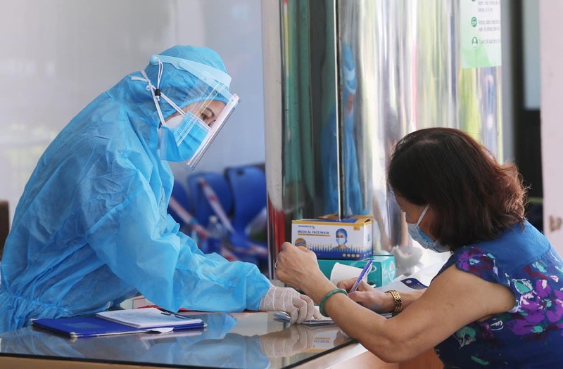 Nhân viên y tế hướng dẫn người dân khai báo y tế (Ảnh: Lê Bảo - Minh Thùy) 
