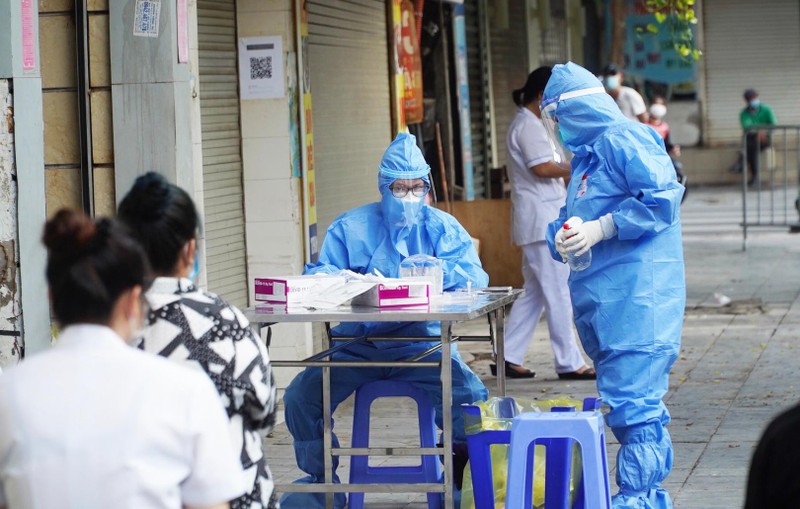 Nhân viên y tế lấy mẫu xét nghiệm COVID-19 cho người dân ở khu vực bên ngoài Bệnh viện Hữu nghị Việt Đức (Ảnh - Minh Nhân) 