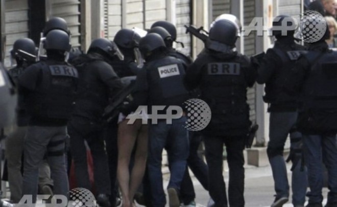 Cảnh sát Pháp dẫn giải một kẻ bị bắt trong cuộc đột kích vào căn hộ ở St Denis (Nguồn: AFP)