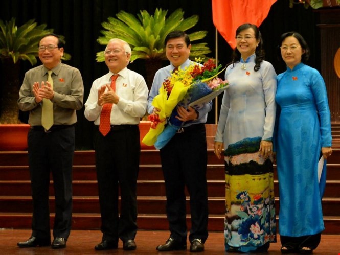 Chủ tịch UBND TP.HCM Nguyễn Thành Phong (giữa) nhận hoa chúc mừng từ ông Lê Hoàng Quân và bà Nguyễn Thị Quyết Tâm - Ảnh: Diệp Đức Minh