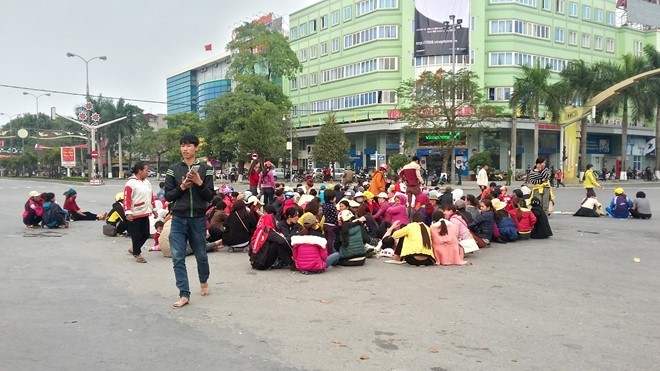 Người dân Sầm Sơn ngồi la liệt dưới lòng đường ngã tư đại lộ Lê Lợi - Trần Phú. Ảnh: Nguyễn Dương.
