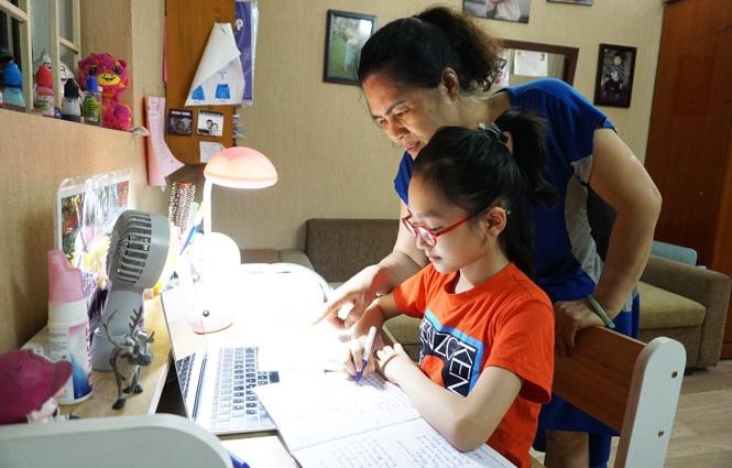 Phụ huynh trợ giúp con khi học trực tuyến - Ảnh: Hanoimoi.com.vn