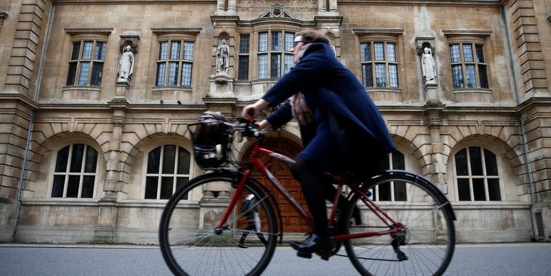 Một người phụ nữ đi xe đạp bên cạnh trường Oriel College ở Oxford, Anh (ảnh: Thomson Reuters)