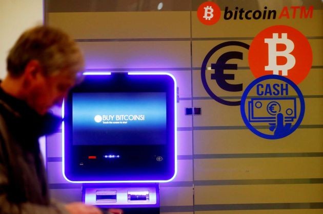 Một người đàn ông đi ngang qua một cây ATM bitcoin ở Vilnius, Litva. Ảnh: CNBC