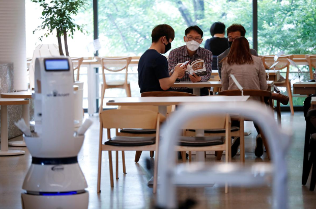 Khách hàng đang chờ đợi phục vụ tại một quán cà phê ở Hàn Quốc nơi robot pha chế sẽ thay thế hoàn toàn cho vai trò của con người. Ảnh: Reuters