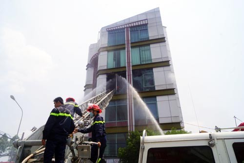 Cảnh sát chữa cháy dùng xe thang dập đám cháy. Ảnh: Nguyệt Triều