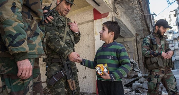 Một sĩ quan cao cấp quân đội Syria nói chuyện với em bé trong khu vực vừa giải phóng ở Aleppo